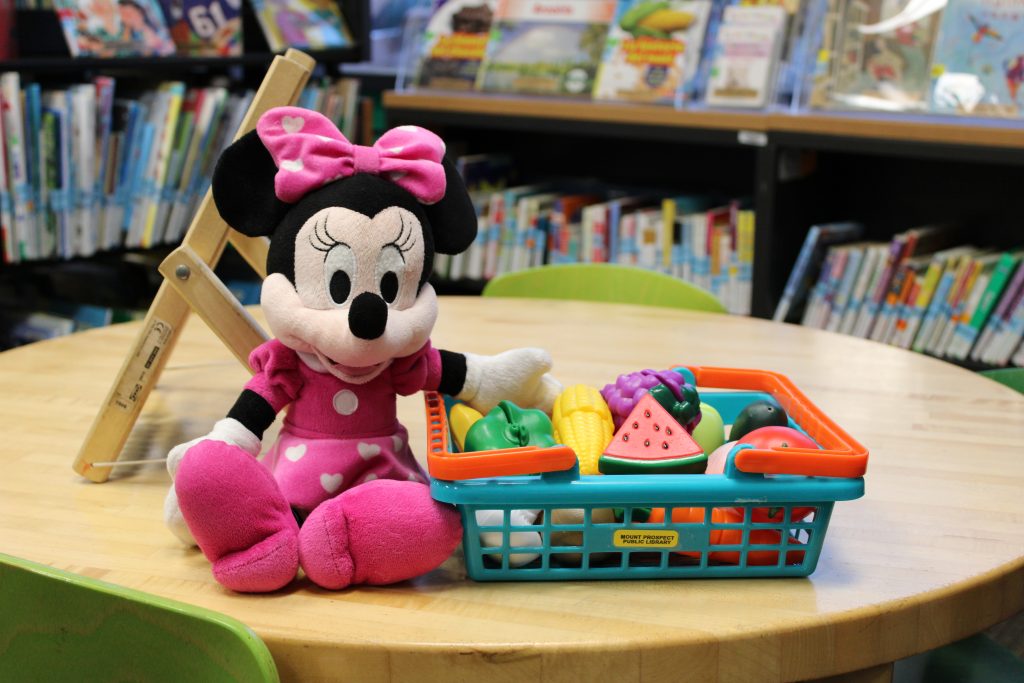 Minnie Mouse plush toy next to basket of plastic toy fruit
