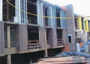Construction, December 2003. Showing front exterior of the library looking north with lumber and two construction workers visible.