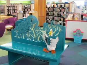Turquoise metal bench with Monty the duck reading a book.