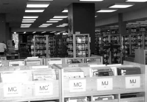 Interior view of the library main floor showing the video and record collection, circa 1987. Black and white.