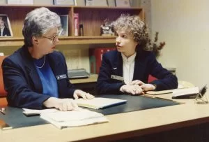 Patricia Kelly and Marilyn Genther sitting and talking in office, circa 1990.