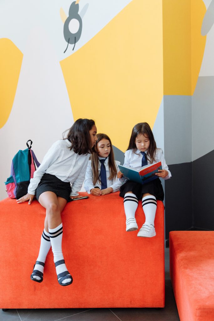 Three schoolgirls sitting and looking at a book.