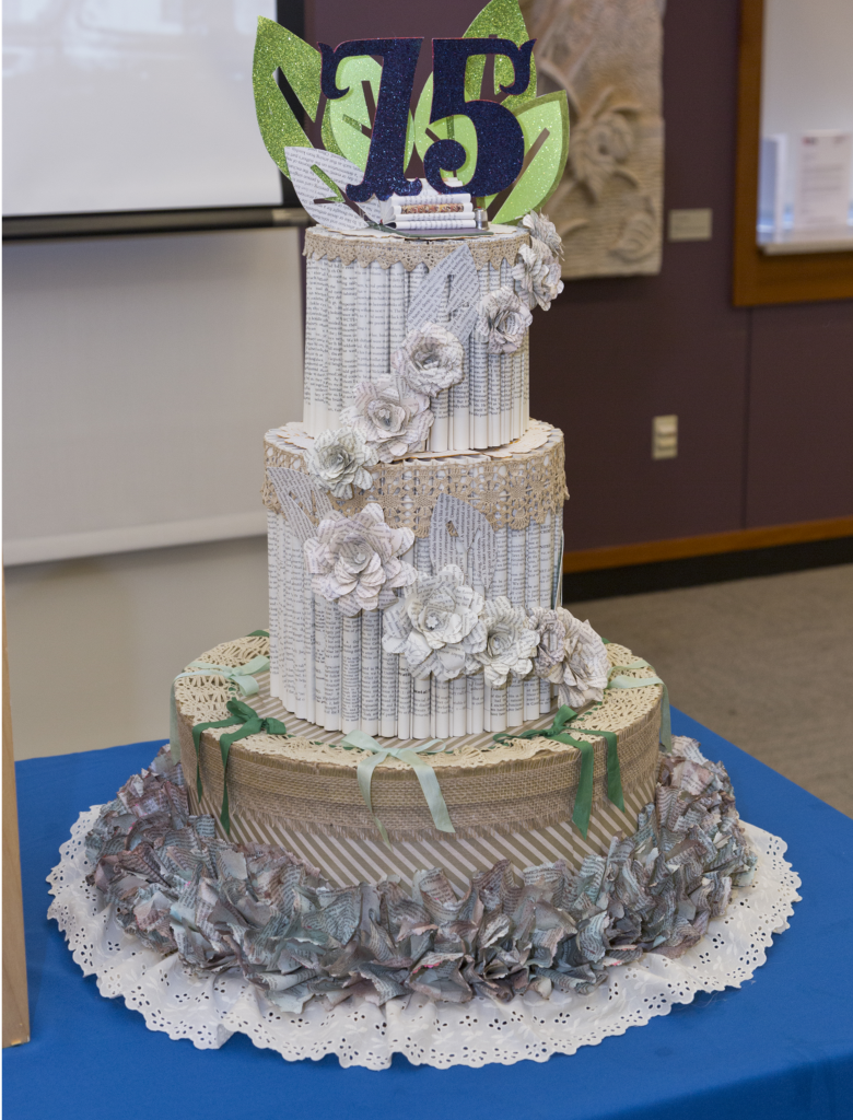 Three-tier 75th anniversary style cake made of book pages, with decorative flowers made of book pages.