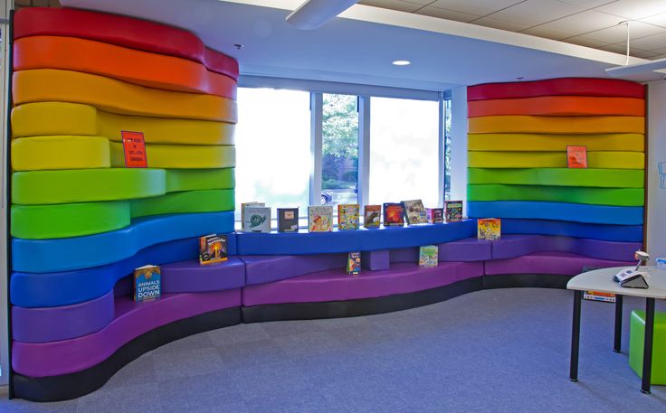 A curved rainbow colored wall with book displays.