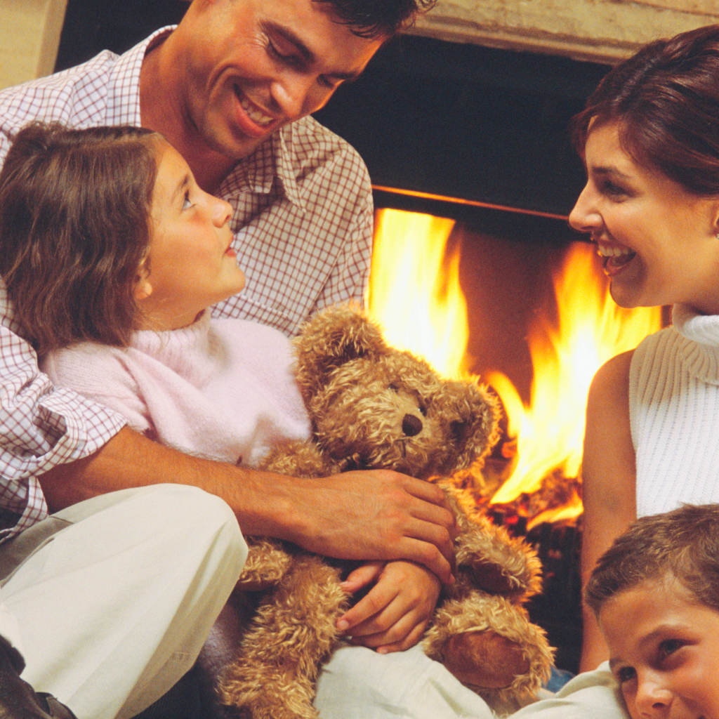 A family sits in front of the fireplace together.