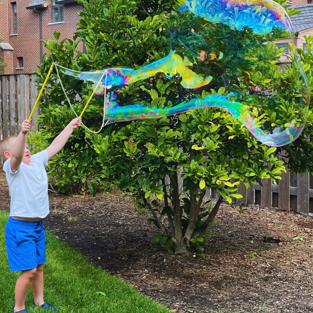 Little boy uses bubble tool to make a giant bubble.